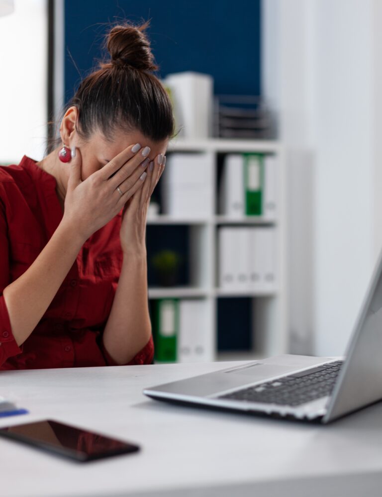 Sad entrepreneur in red shirt holding face in palms.